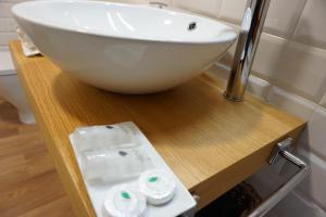 a white bowl sink on a wooden counter in a bathroom at Apartamentos Turísticos El Peñón in Tapia de Casariego