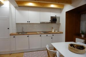 a kitchen with white cabinets and a table and a microwave at Apartamentos Turísticos El Peñón in Tapia de Casariego