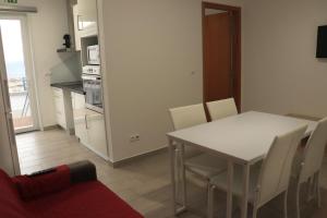 una cucina e una sala da pranzo con tavolo e sedie bianchi di Faial Marina Apartments 2 a Horta