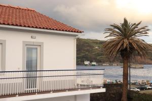 a house with a palm tree next to the water at Faial Marina Apartments 2 in Horta