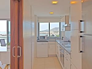 a kitchen with white appliances and a large window at Cofradia Penthouse in Alcudia