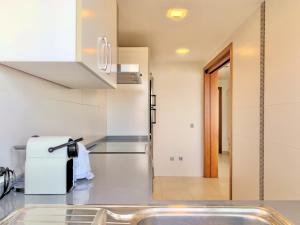 a kitchen with a sink and a refrigerator at Cofradia Penthouse in Alcudia