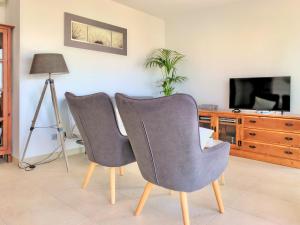 two gray chairs in a living room with a television at Cofradia Penthouse in Alcudia