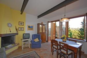 a living room with a dining room table and a tv at Tenuta la Cipresseta in Monsanto