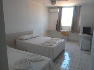 a room with two beds and a window and a television at Pousada Praia De Guarajuba in Guarajuba