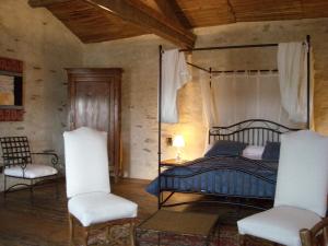 a bedroom with a canopy bed and two chairs at La Tour des Laudes in Breuil-Barret