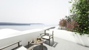 a balcony with a table and chairs overlooking the water at Oia Memories Suites in Oia