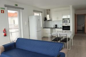 a living room with a blue couch and a kitchen at Faial Marina Apartments 2 in Horta