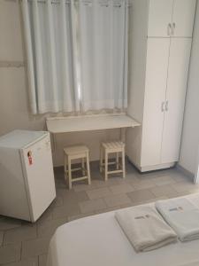 a room with two beds and a desk and cabinets at Vista Oceanica Pousada in Marataizes