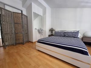 a white bedroom with a black and white bed and a fan at Appartement VUE MER TERRASSE CLIM WIFI in Banyuls-sur-Mer
