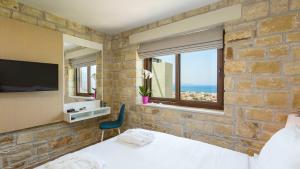キサモスにあるVilla Emilia I Luxury, amazing seaview, next to the townの石壁のベッドルーム(ベッド1台、テレビ付)