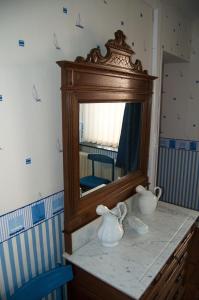 un miroir sur une commode avec deux vases dessus dans l'établissement Chambres d'hôtes de la Quairelle, à Gerpinnes