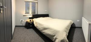 1 dormitorio con cama, lámpara y ventana en London Gate Lodge - Private En-suite rooms, Kings Lynn, central location en Kings Lynn