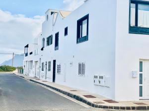 une rangée de bâtiments blancs sur le côté d'une rue dans l'établissement Canaryislandshost l Famara Surfer, à Famara