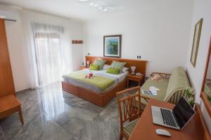 a bedroom with a bed and a desk with a laptop at Best Western Hotel Martello in Lampedusa
