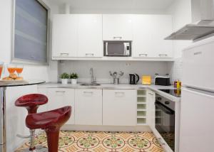una cucina con armadi bianchi e uno sgabello rosso di Casa Muntaner a Barcellona