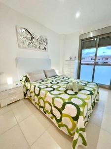 a bedroom with a green and white bed and a window at Samsara Beach in Port d'Alcudia