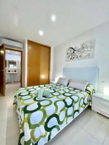 a bedroom with a large bed with a green and white blanket at Samsara Beach in Port d'Alcudia