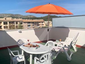 a table and chairs with an umbrella on a balcony at Samsara Beach in Port d'Alcudia