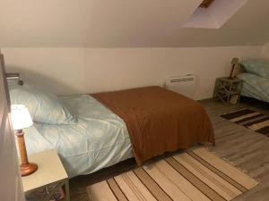 ein Schlafzimmer mit einem Bett, einem Tisch und einer Lampe in der Unterkunft Confortable duplex au cœur de la campagne Picarde à 1h de Paris in Biermont