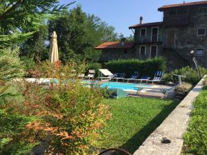 a pool with chairs and a umbrella next to a house at Casale Antico Borgo in Colico