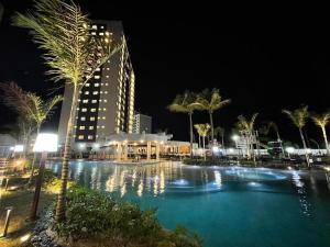 a swimming pool at night with a building and palm trees at Salinas Exclusive Resort in Salinópolis