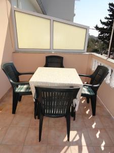 a table and chairs on a balcony with two windows at Apartments & Rooms Karmela in Banjol