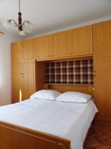 1 dormitorio con 1 cama grande y armarios de madera en Apartments & Rooms Karmela, en Banjol
