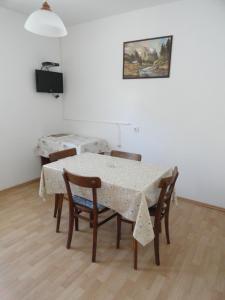 a dining room table and chairs with a table and a painting at Apartments & Rooms Karmela in Banjol