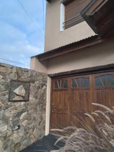een huis met een houten garagedeur en een stenen muur bij Amancay in Tandil