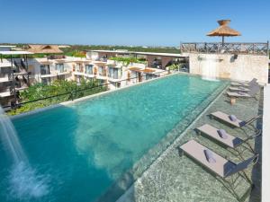 a swimming pool with chaise lounges and a water fountain at Naala Tulum in Tulum