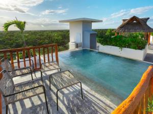 a pool on the balcony of a house with two chairs at Naala Tulum in Tulum