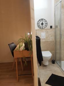 baño con escritorio, aseo y reloj en Le Havre de Gaïa, en Charnècles