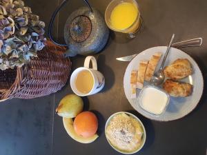- une table avec des assiettes de produits pour le petit-déjeuner et des boissons dans l'établissement Le Havre de Gaïa, à Charnècles