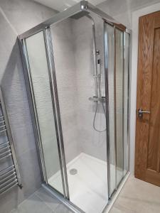 a shower with a glass door in a bathroom at Valley View Cottage in Rothbury