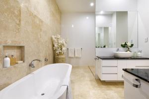 a white bathroom with a tub and a sink at Exquisite Riverside Living, Noosaville in Noosaville +24 photos