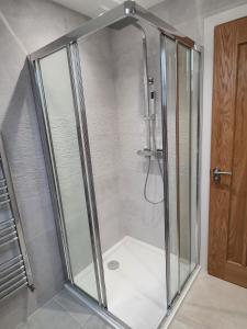 a shower with a glass door in a bathroom at Copper Cottage in Rothbury