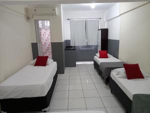 a room with two beds with red pillows at Hotel PS Itaboraí in Itaboraí