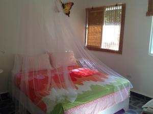 a bedroom with a bed with a mosquito net at Bungalow Natura Village in Sosúa