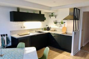a kitchen with black cabinets and a white counter top at Charmant T3 cœur de ville avec parking in Limoges