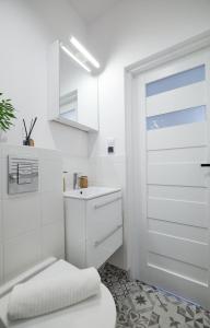 uma casa de banho branca com um lavatório e uma porta em Mikroklimatyczny apartament dla 4 osób em Szklarska Poręba