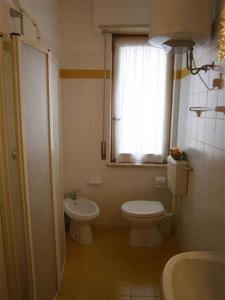 a bathroom with a toilet and a sink and a window at Two-Bedroom Apartment in Bibione VIII in Bibione