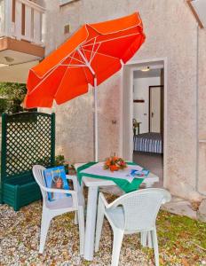 ビビオーネにあるHoliday home in Bibione 24390のテーブルと椅子2脚(オレンジの傘付)
