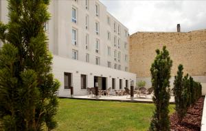 un grand bâtiment blanc avec des arbres au premier plan dans l'établissement ibis Styles Bordeaux Centre Gare, à Bordeaux