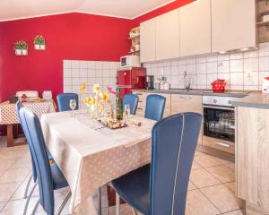 a kitchen with a table with blue chairs and a red wall at Apartment in Vrbnik/Insel Krk 14527 in Vrbnik