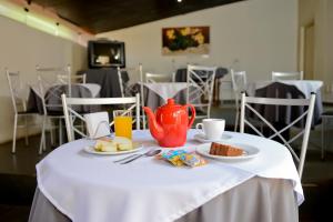 a table with a tea pot and plates of food at Hotel Pousada Jaguariuna in Jaguariúna