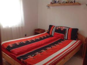 a bed with a red comforter on top of it at Apartment Balatonbereny 2 in Balatonberény