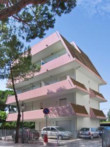 un edificio rosa con coches estacionados frente a él en Sweet Home Appartamenti, en Bellaria-Igea Marina