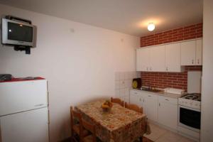 eine Küche mit einem Tisch mit Stühlen und einem Kühlschrank in der Unterkunft One-Bedroom Apartment Silo near Sea 1 in Šilo