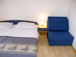 a bedroom with a bed and a blue chair at Studio Crikvenica 8 in Dramalj